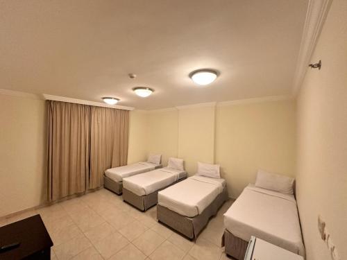 a hospital room with three beds and a window at ALBILAD ROYA HOTEL in Makkah
