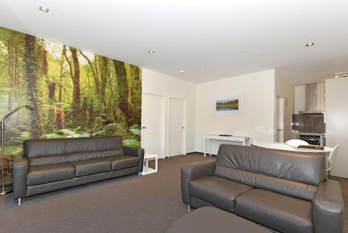 a living room filled with furniture and a large window at Aspen Court Franz Josef in Franz Josef