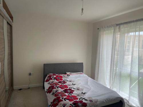 1 dormitorio con 1 cama con manta roja y blanca en Lovely 1 bed flat with 1 min walk to metro station, en Hendon