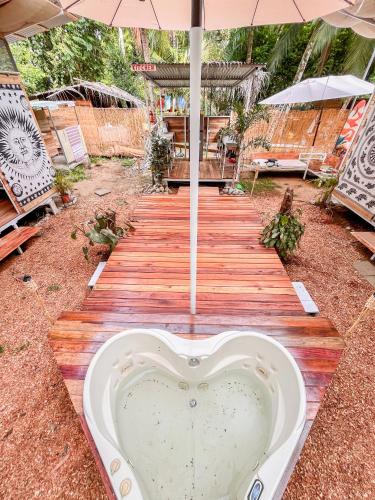 a heart shaped bath tub on a wooden walkway with an umbrella at Nomadic Surf Camp in Uvita