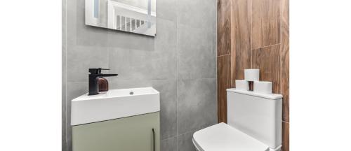 a bathroom with a white toilet and a sink at Hip & Happening: 4BR Urban Gem for Large Groups in Harrow