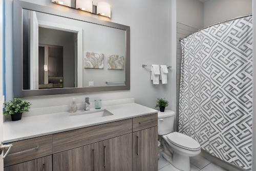 La salle de bains est pourvue d'un lavabo, de toilettes et d'un miroir. dans l'établissement Trifecta Luxury Serviced Apartment in Uptown CLT, à Charlotte