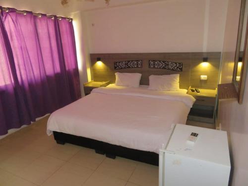 a bedroom with a large bed and purple curtains at Best hotel aqaba in Aqaba