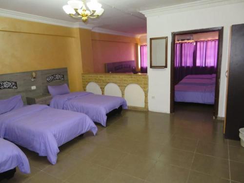 Best hotel aqaba في العقبة: غرفة بها ثلاثة أسرة مع ملاءات أرجوانية