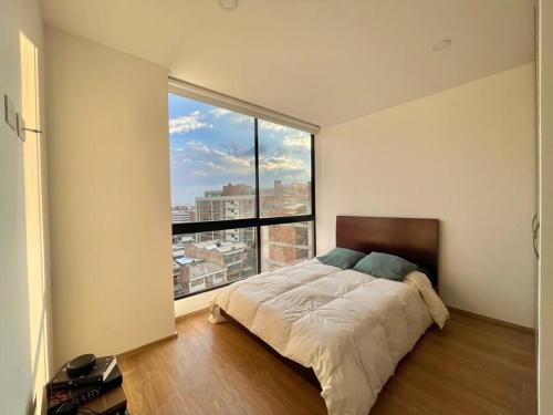 ein Schlafzimmer mit einem Bett und einem großen Fenster in der Unterkunft SkyLine Mountains Sauna Gym Luxury Apto in Bogotá