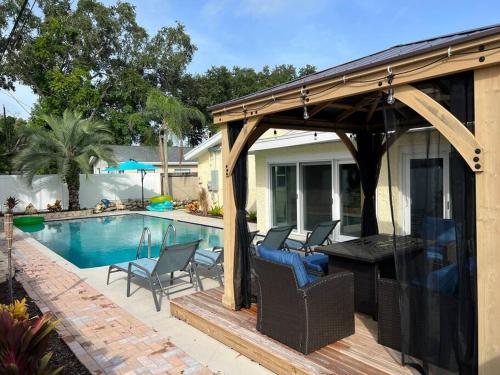 a pavilion with chairs and a table next to a pool at Tropical Pool & Patio Bar minutes to the beach! in Seminole