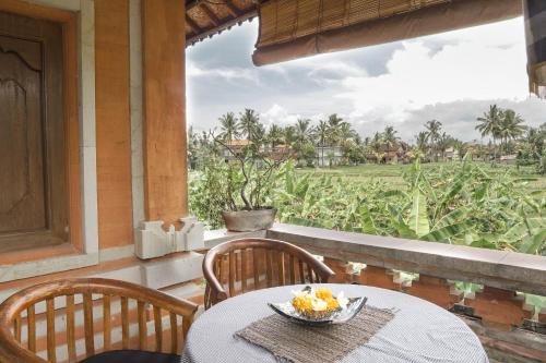 a table with a bowl of fruit sitting on a balcony at Nirwa 1 Ubud Guesthouse in Ubud