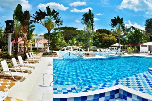 Aguazul的住宿－CENTRO VACACIONAL & HOTEL CAMPESTRE LAGO CENTER，一个带椅子和树木的度假村游泳池