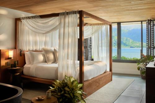 a bedroom with a canopy bed with a view of the ocean at 1 Hotel Hanalei Bay in Princeville