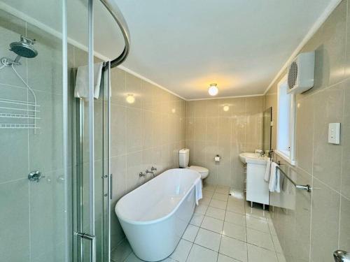 ein Bad mit einer Badewanne, einem Waschbecken und einer Dusche in der Unterkunft Maple Grove in Katoomba