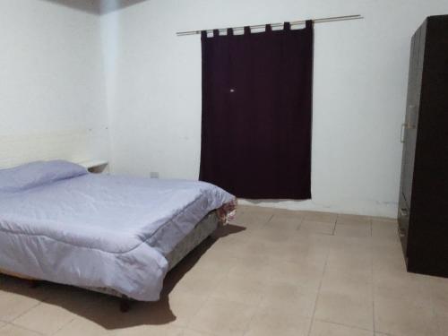 1 dormitorio con cama y cortina negra en Departamentos teuli en Puerto San Julián