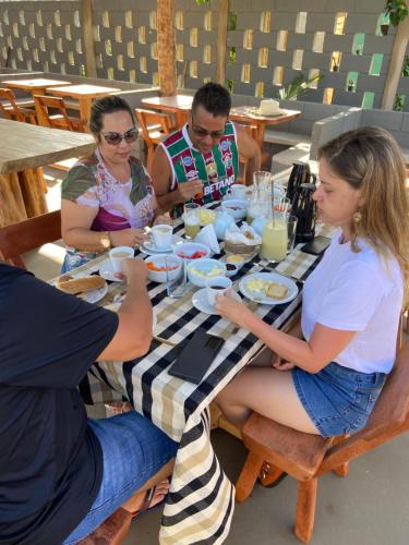 a group of people sitting at a table eating food at Jardim dos Milagres Suítes in São Miguel dos Milagres