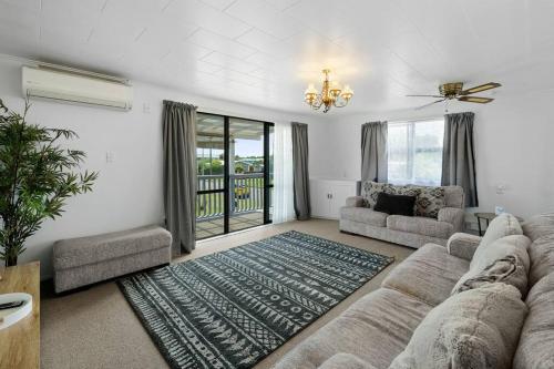 sala de estar con sofá y alfombra en Whole House Sleeps 12 AC -Wifi - Pool, en Gisborne
