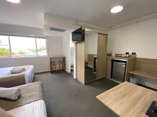 a hotel room with two beds and a kitchen and a counter at Huskisson Beach Motel in Huskisson