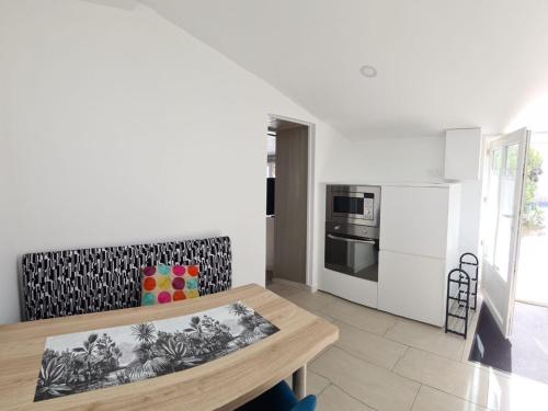 une cuisine blanche avec une table et un réfrigérateur dans l'établissement Charmante maison rénovée avec jardin commun, proche plage et commerces, idéale pour 2 personnes - FR-1-426-509, à Saint-Vincent-sur-Jard