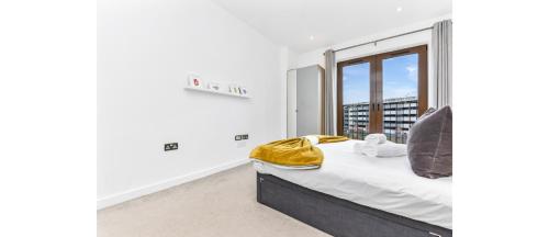 ein Schlafzimmer mit einem Bett und einem großen Fenster in der Unterkunft Metropolitan Luxury: Chic 2BR Flat in St. Albans in St Albans