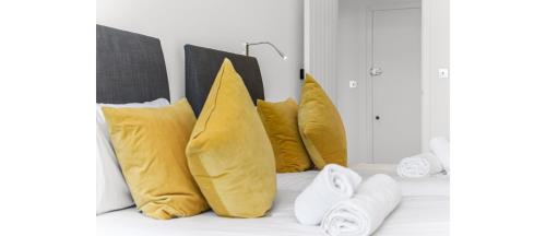 a group of yellow pillows sitting on a shelf at Metropolitan Luxury: Chic 2BR Flat in St. Albans in St. Albans