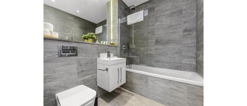 a bathroom with a toilet and a sink and a tub at Metropolitan Luxury: Chic 2BR Flat in St. Albans in St. Albans