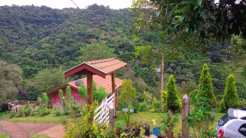 a garden with a wooden pavilion in front of a mountain at Sonho na Serra Chalé 1 in Gonçalves