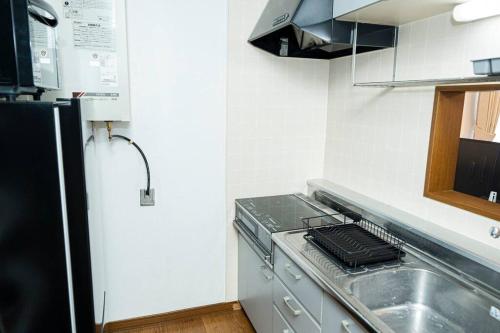 a small kitchen with a sink and a stove at 2024年3月新規オープン-最大16名-駐車場2台無料-大画面ゲーム&映画鑑賞-札幌中心部まで車で10分 in Tsukisappu