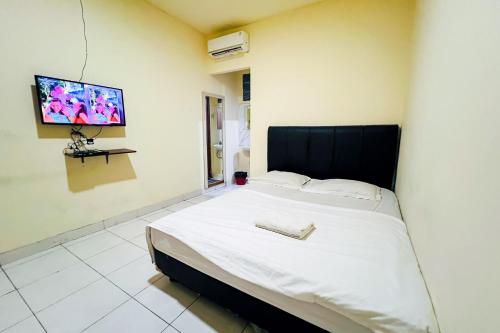 1 dormitorio con 1 cama y TV en la pared en Wisma Berkat Mitra RedDoorz, en Yakarta