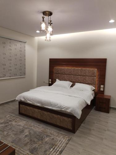 a bedroom with a large bed and a chandelier at شقق الياسمين in Medina