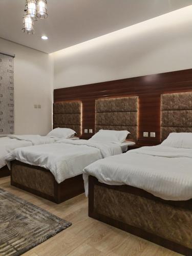 una camera con tre letti e lenzuola bianche di شقق الياسمين a Medina