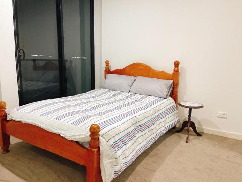a bed with a wooden headboard in a bedroom at Parramatta New Paint 2B2B High Floor apt next to Train and shopping in Sydney