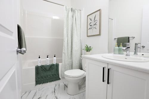 a white bathroom with a toilet and a sink at Stylish Retreat with King Bed, Long Stays, WEM, Disney+ in Edmonton