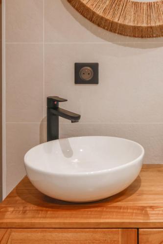 - un évier blanc sur un comptoir en bois avec un robinet dans l'établissement Lapis lazuli - T3 parking proche lac, à Annecy