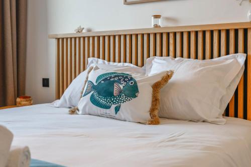 Una cama con almohadas blancas con un pescado. en Lapis lazuli - T3 parking proche lac, en Annecy