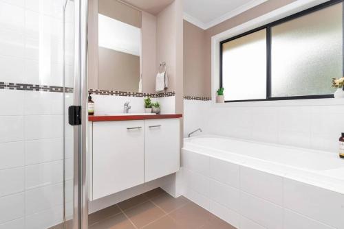 a white bathroom with a tub and a sink and a bath tubermottermottermott at Entire home in Mount Barker in Mount Barker