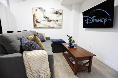 a living room with a gray couch and a wooden table at Stylish Retreat with King Bed, Long Stays, WEM, Disney+ in Edmonton