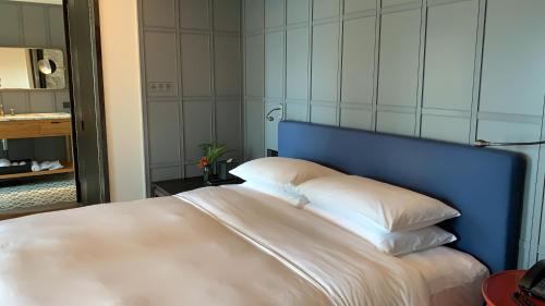 a bed with a blue headboard and two pillows at Hotel Kapok Shenzhen HouHai (Close to Shenzhen Bay) in Shenzhen