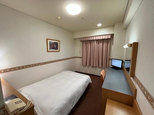 Habitación con cama y escritorio con ordenador. en Hotel Alpha-One Miyoshi en Miyoshi