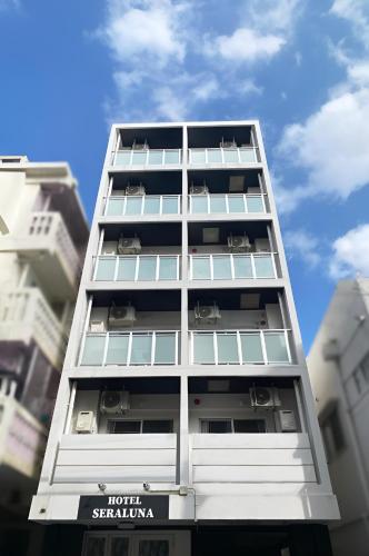 a tall white apartment building with windows at Hotel SERA LUNA -ホテル セラルナ- in Naha