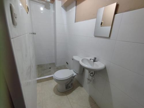 La salle de bains blanche est pourvue de toilettes et d'un lavabo. dans l'établissement Hospedaje LOS OLIVOS, à Ayacucho