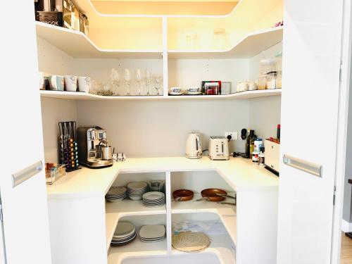 a kitchen with white shelves with dishes and appliances at Summer Holiday 4 bedrooms house in Hamilton with pool and spa in Hamilton