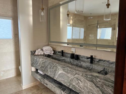a bathroom with a large mirror and a stone sink at Boskenvid Hotel - Romantic Treehouses & Skypool in Valle de Guadalupe