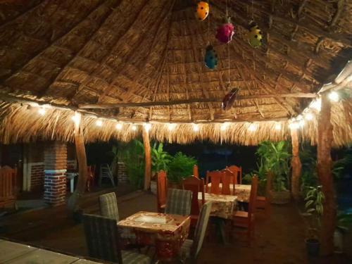un restaurante con techo de paja, mesas y sillas en Restaurante El Escondite en Ometepe