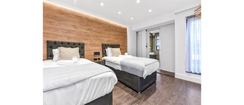 a hotel room with two beds and a window at Luxury Abode: 5-Bed Haven Ideal for Big Groups! in London