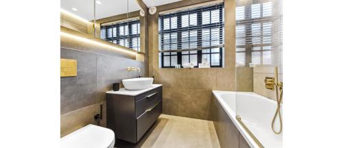 Luxury Abode: 5-Bed Haven Ideal for Big Groups! في لندن: حمام مع حوض وحوض استحمام ومرحاض