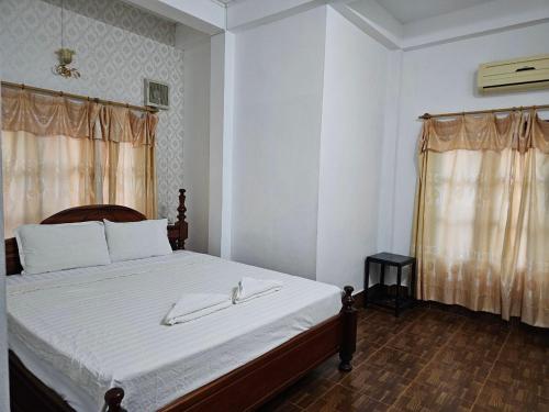 a bedroom with a bed with white sheets and a window at Maylayguesthouse1 in Vang Vieng