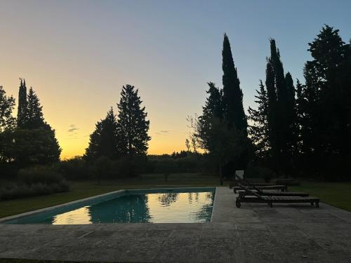 una piscina con bancos y una puesta de sol en el fondo en Capilla-Casa de campo en Capilla del Señor