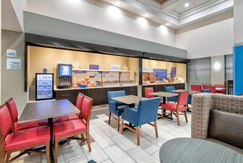 a restaurant with tables and chairs and a counter at Holiday Inn Express Hotel & Suites Dallas Fort Worth Airport South by IHG in Irving