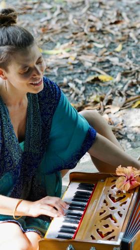 a woman is sitting next to a piano at Casa Patricia in Uvita