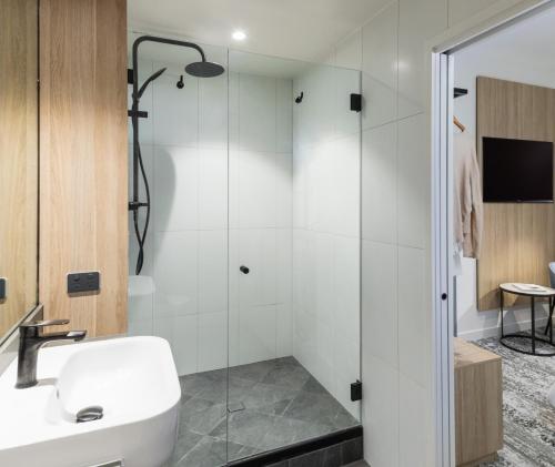a bathroom with a sink and a shower at Oaks Cairns Hotel in Cairns