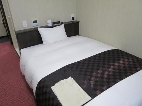 a hotel room with a large bed with white sheets at Okawa Riverside Hotel in Ōkawa