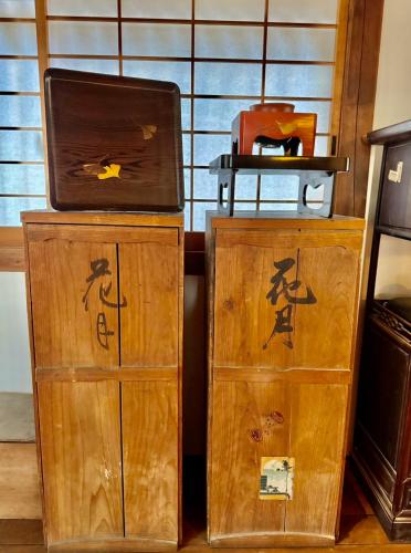 two wooden cabinets with writing on them in a room at Kagetsu Taisyokan in Takeo