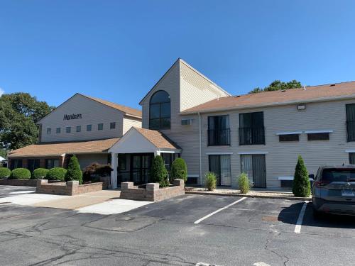 a building with a car parked in a parking lot at The Mariner Resort Cape Cod by The Red Collection in West Yarmouth